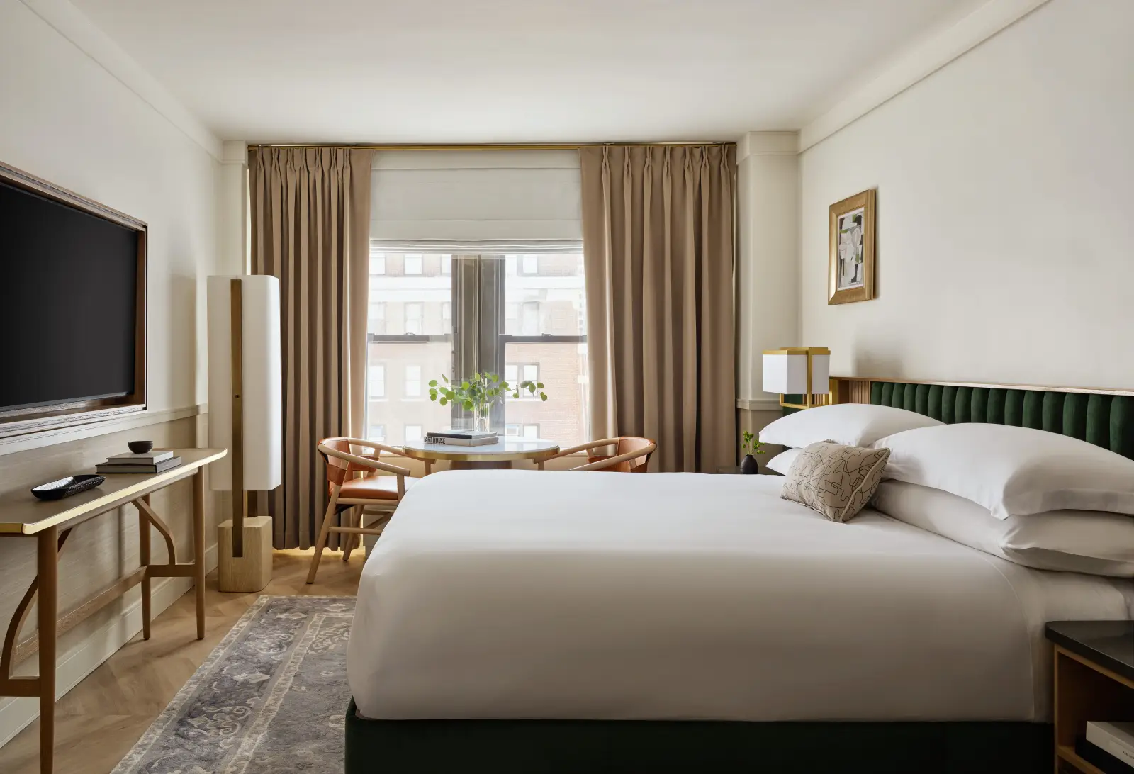 Modern guest room at Kimpton Ashbel New York with king bed, city-view window, soft neutral decor and seating area.
