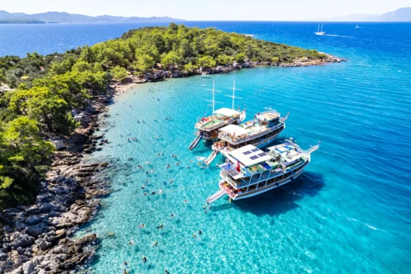 ALT text: Aerial view of tour boats anchored at Incekum Beach in Marmaris with turquoise water and swimmers along the rocky coastline