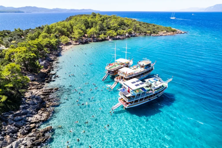 ALT text: Aerial view of tour boats anchored at Incekum Beach in Marmaris with turquoise water and swimmers along the rocky coastline