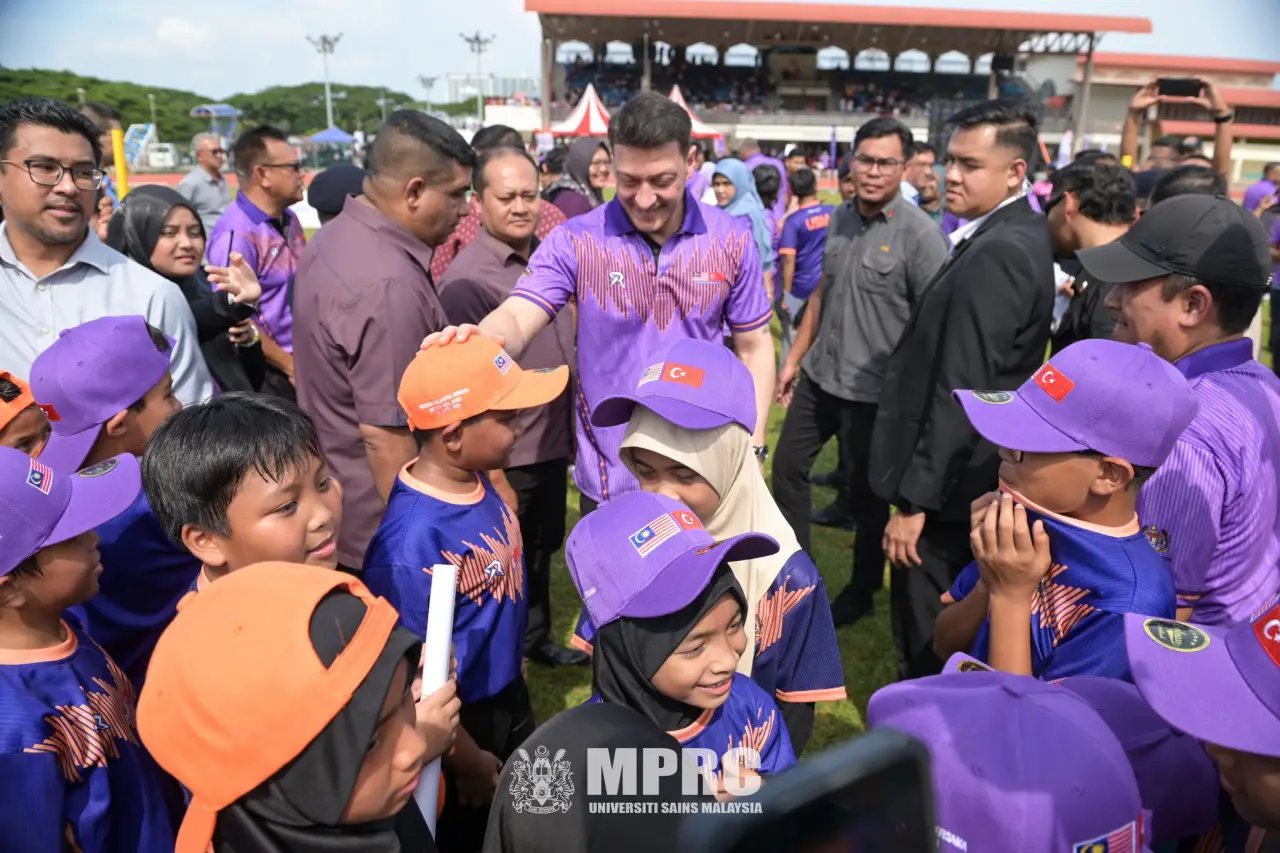 Mesut Özil interacts with children during a football clinic at Universiti Sains Malaysia in Penang, surrounded by young players and spectators