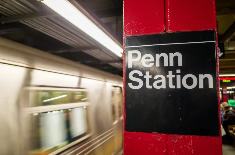 Penn Station subway platform sign with a passing train in New York City.