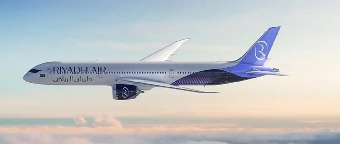 Riyadh Air Boeing 787-9 Dreamliner flying above clouds in the airline’s purple livery