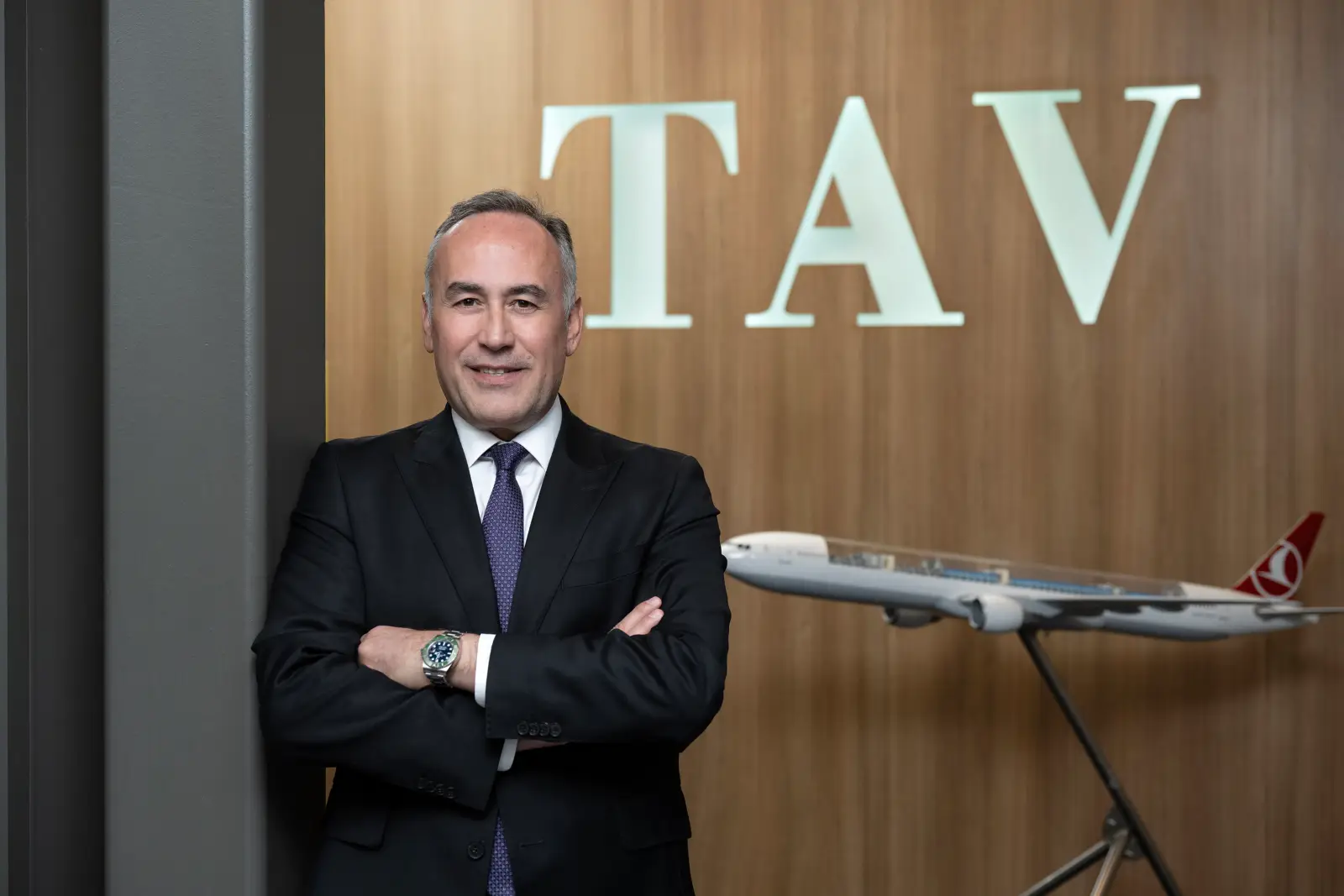 Serkan Kaptan, Chief Executive Officer of TAV Airports, standing beside a Turkish Airlines aircraft model in a corporate office.