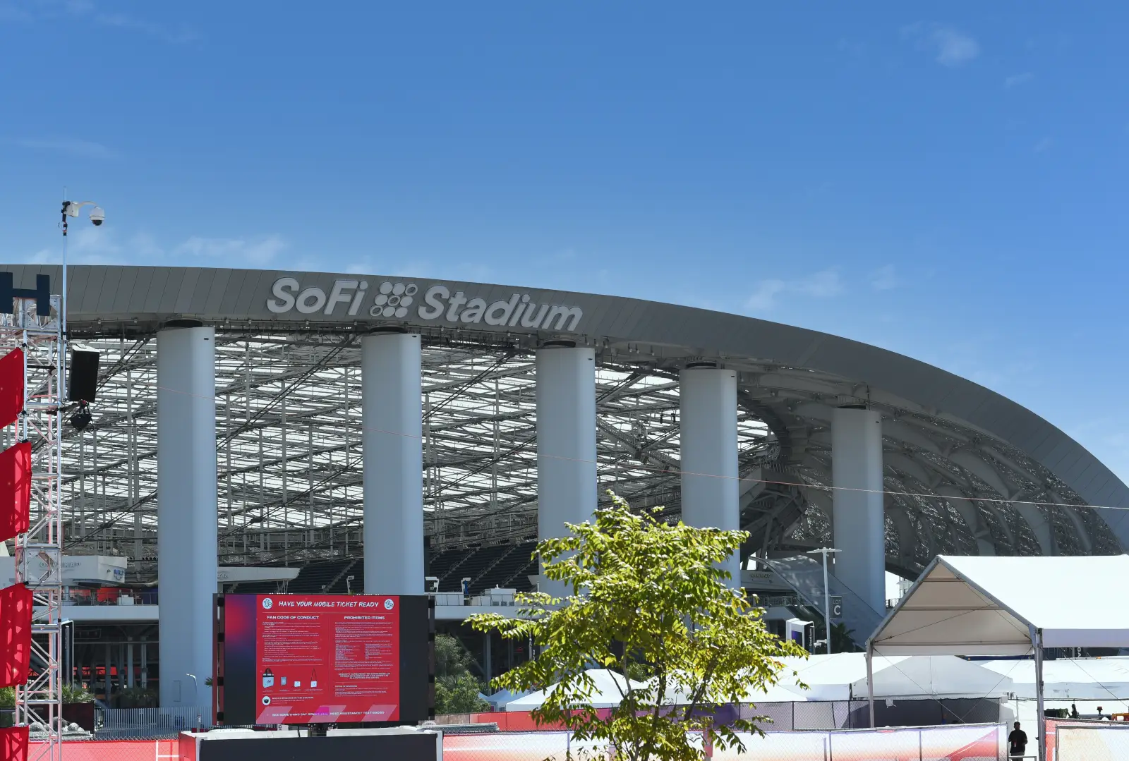 How To Get To Fifa World Cup Matches In Los Angeles Without A Car 2 Exterior daytime view of SoFi Stadium in Inglewood, California, showing the venue's distinctive curved roof structure supported by large white columns under a clear blue sky.
