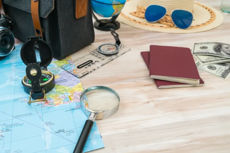Travel planning desk with passports, world map, compass, magnifying glass, camera and US dollars preparing for an international trip