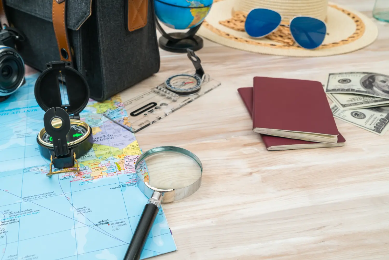 Travel planning desk with passports, world map, compass, magnifying glass, camera and US dollars preparing for an international trip