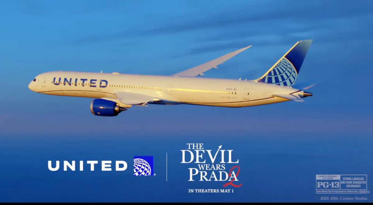 A United Airlines Boeing 787 Dreamliner in standard white and blue livery flies against a twilight blue sky, with the United Airlines logo on the left and The Devil Wears Prada 2 film title and "In Theaters May 1" text on the right, alongside a PG-13 rating notice and 2026 20th Century Studios credit