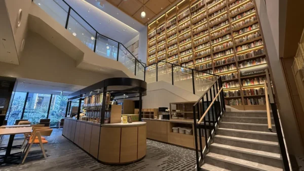 Home 17 Modern SHARE LOUNGE interior at Mercure Tokyu Stay Hiroshima featuring towering bookshelves, seating areas and staircase design.