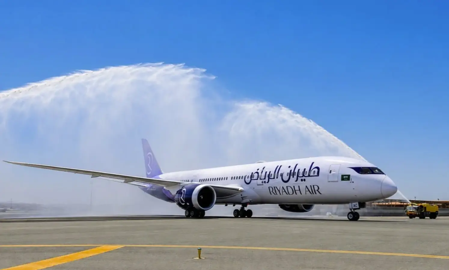 A Riyadh Air Boeing 787 Dreamliner receiving a traditional water cannon salute on the tarmac during an inaugural flight ceremony