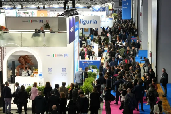 Home 5 Visitors and exhibitors walk through crowded exhibition halls at BIT tourism trade fair in Milan, featuring destination stands and industry networking areas.
