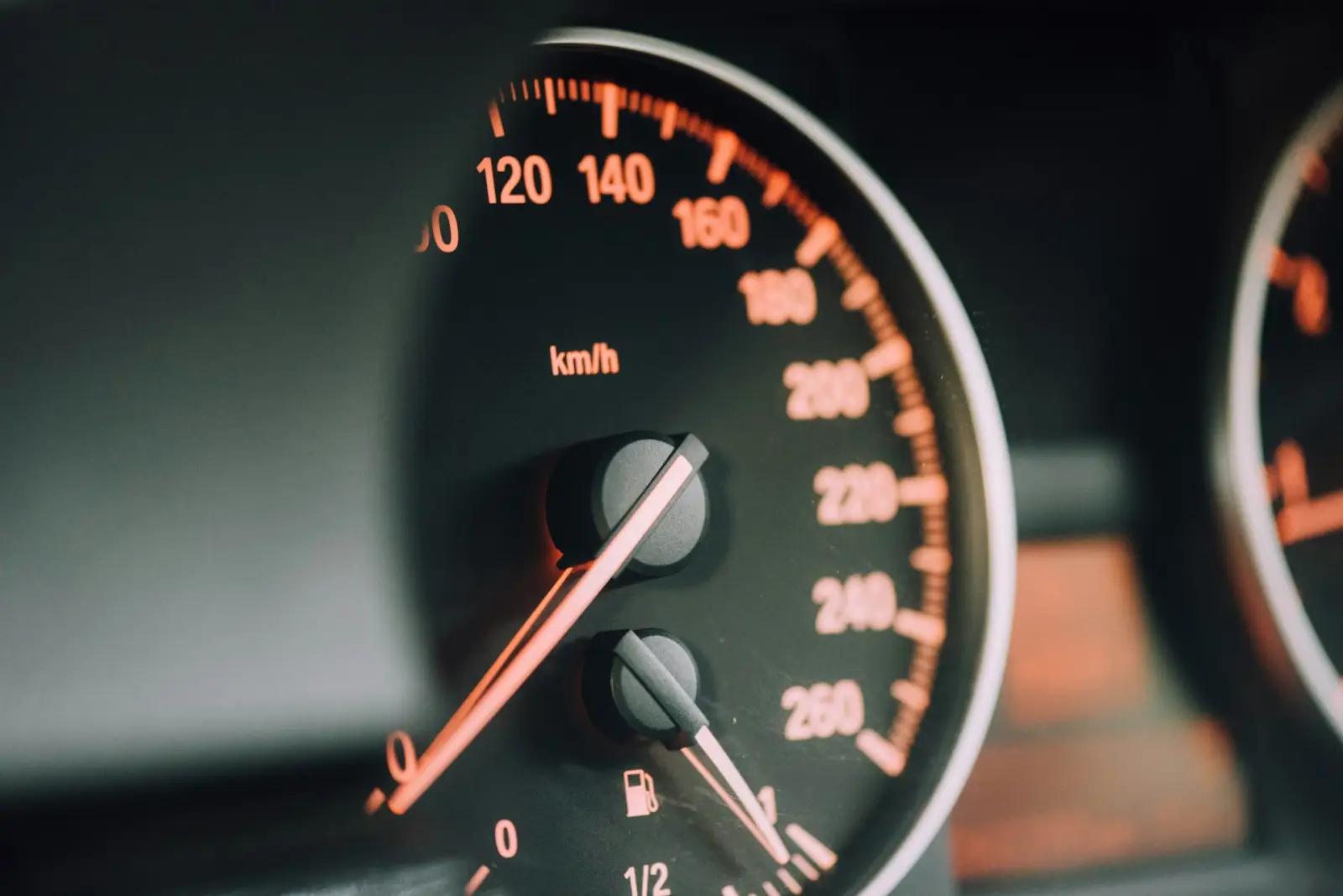 Close-up of a car speedometer and fuel gauge inside a vehicle dashboard.