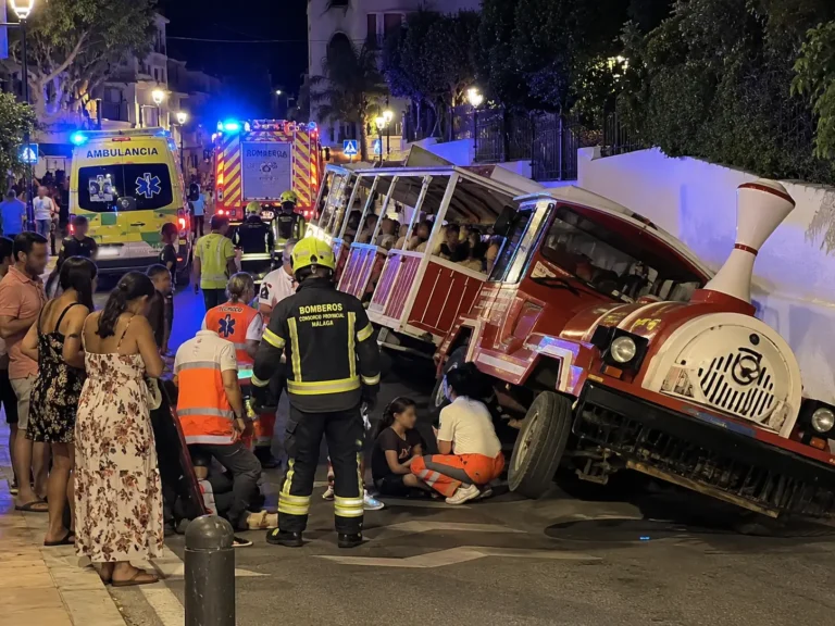 Emergency responders assist passengers after a tourist train overturned in Cártama, Málaga province, Spain, at night