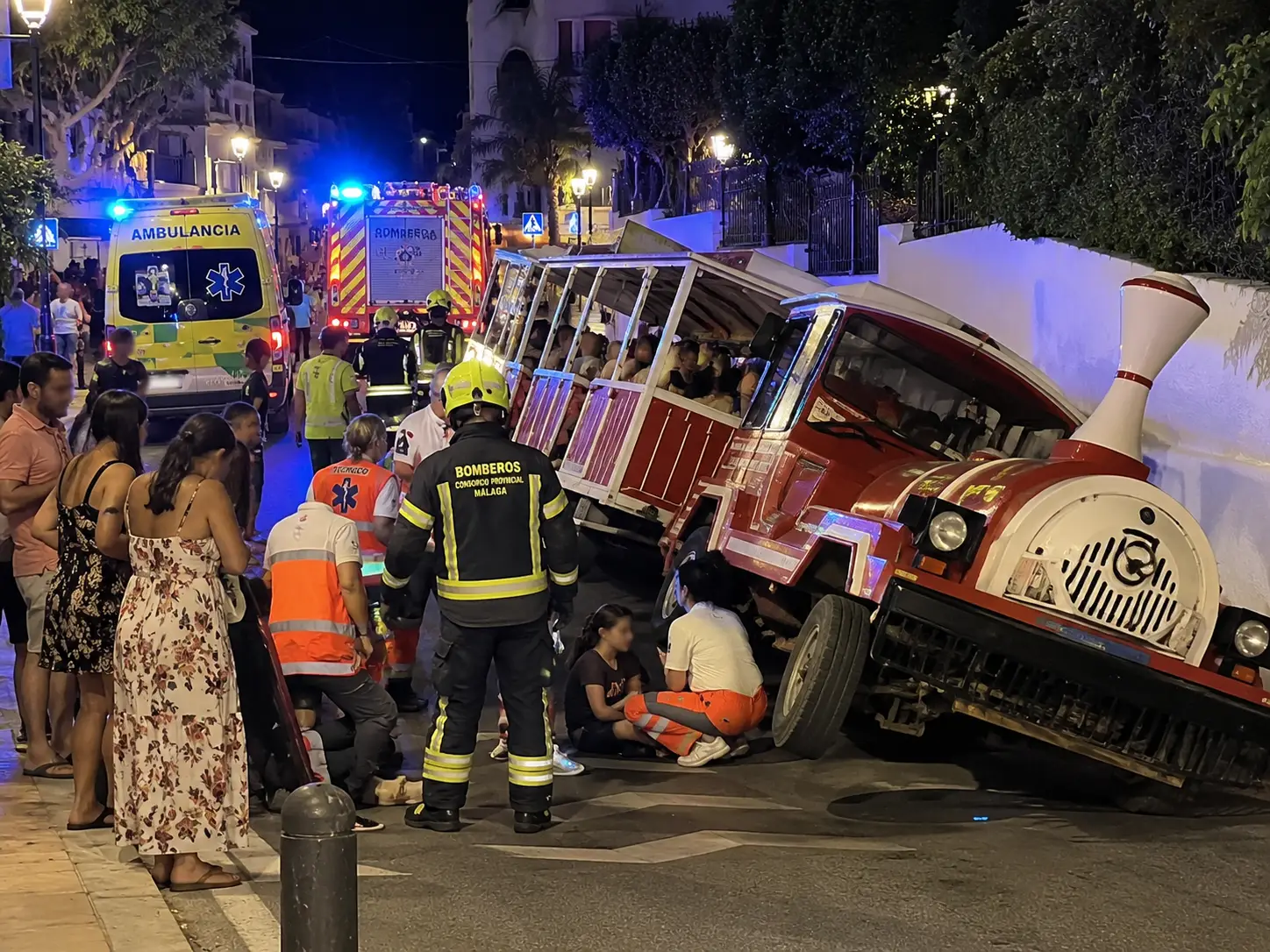 Emergency responders assist passengers after a tourist train overturned in Cártama, Málaga province, Spain, at night