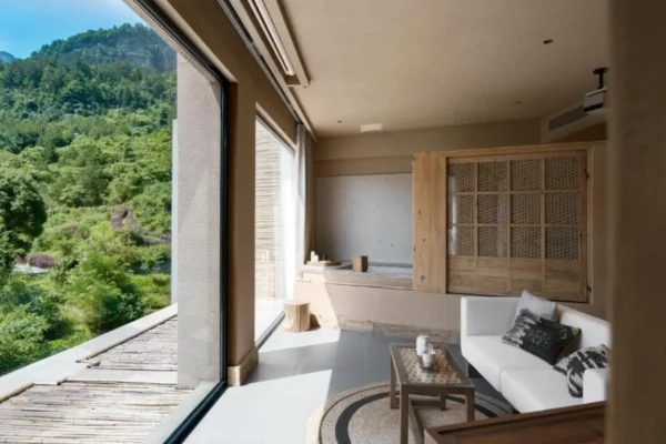 Modern sustainable boutique hotel suite with large panoramic window overlooking green mountains and forest landscape in Chongqing, China