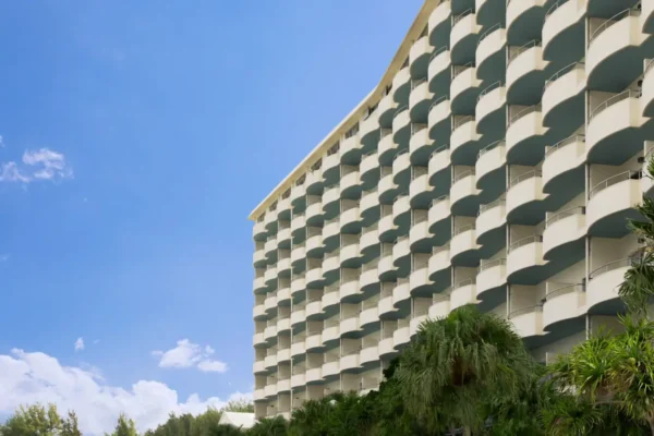 Home 1 Exterior view of Courtyard by Marriott Okinawa Resort featuring curved ocean-view balconies and tropical landscaping in Nago, Japan.