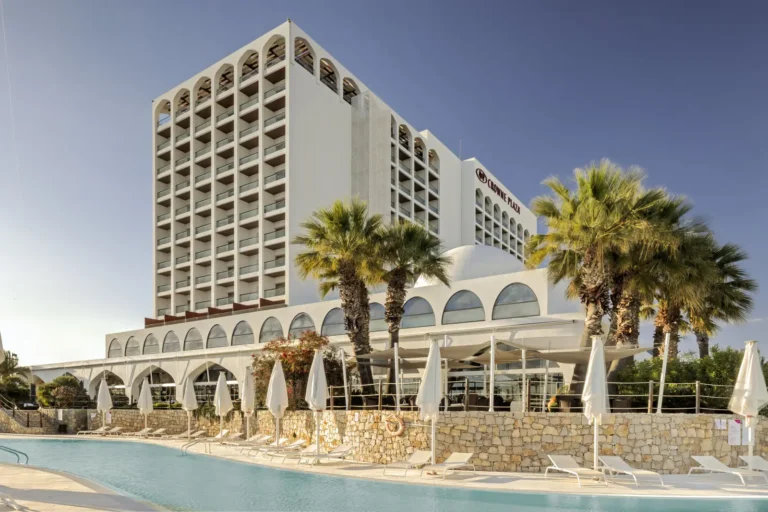 Crowne Plaza Vilamoura resort exterior with pool, sun loungers and palm trees in the Algarve, Portugal