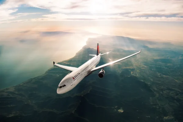 Delta Air Lines passenger aircraft flying above a coastal landscape at sunset