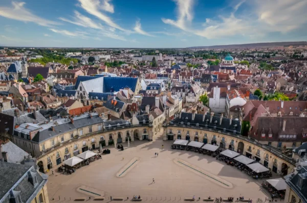 Aerial view of Dijon city centre showing the Place de la Liberation square, classical stone arcades and historic rooftops stretching across the Burgundy skyline