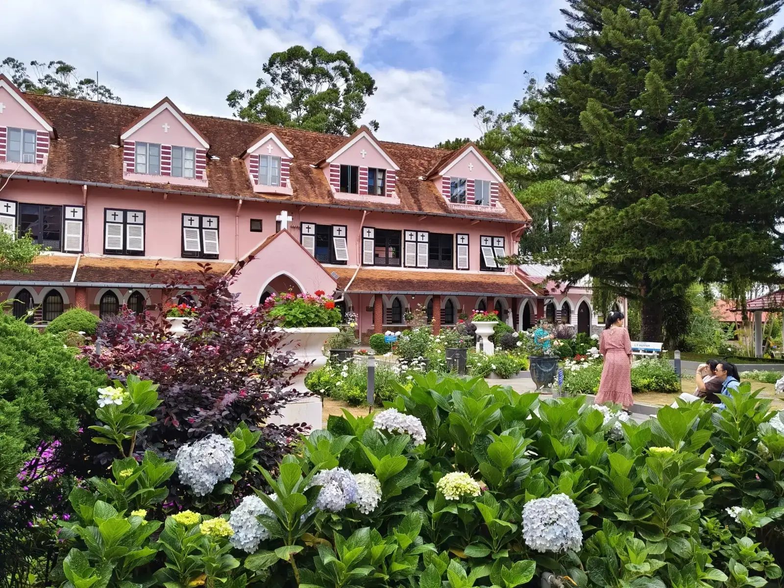 Domaine de Marie Pink Church in Da Lat surrounded by colorful flower gardens and French colonial architecture in Vietnam.