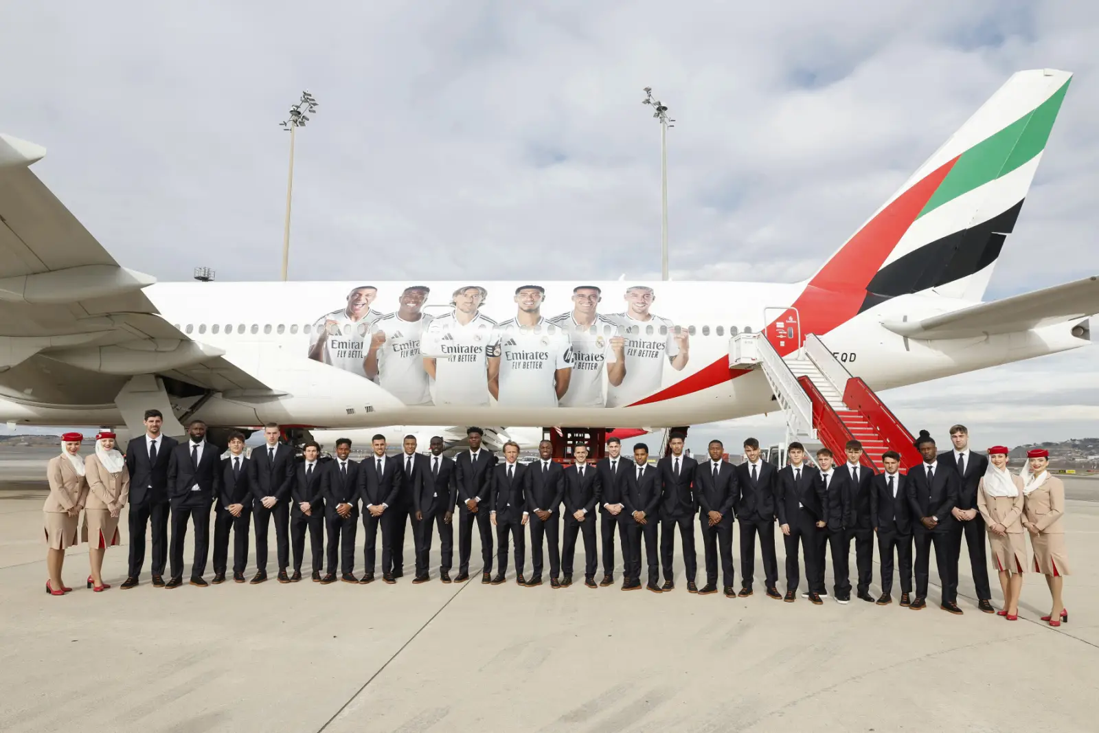 Emirates And Real Madrid Extend Legacy Partnership To 2031 3 Real Madrid players and Emirates cabin crew standing beside a branded Emirates aircraft featuring football-themed livery