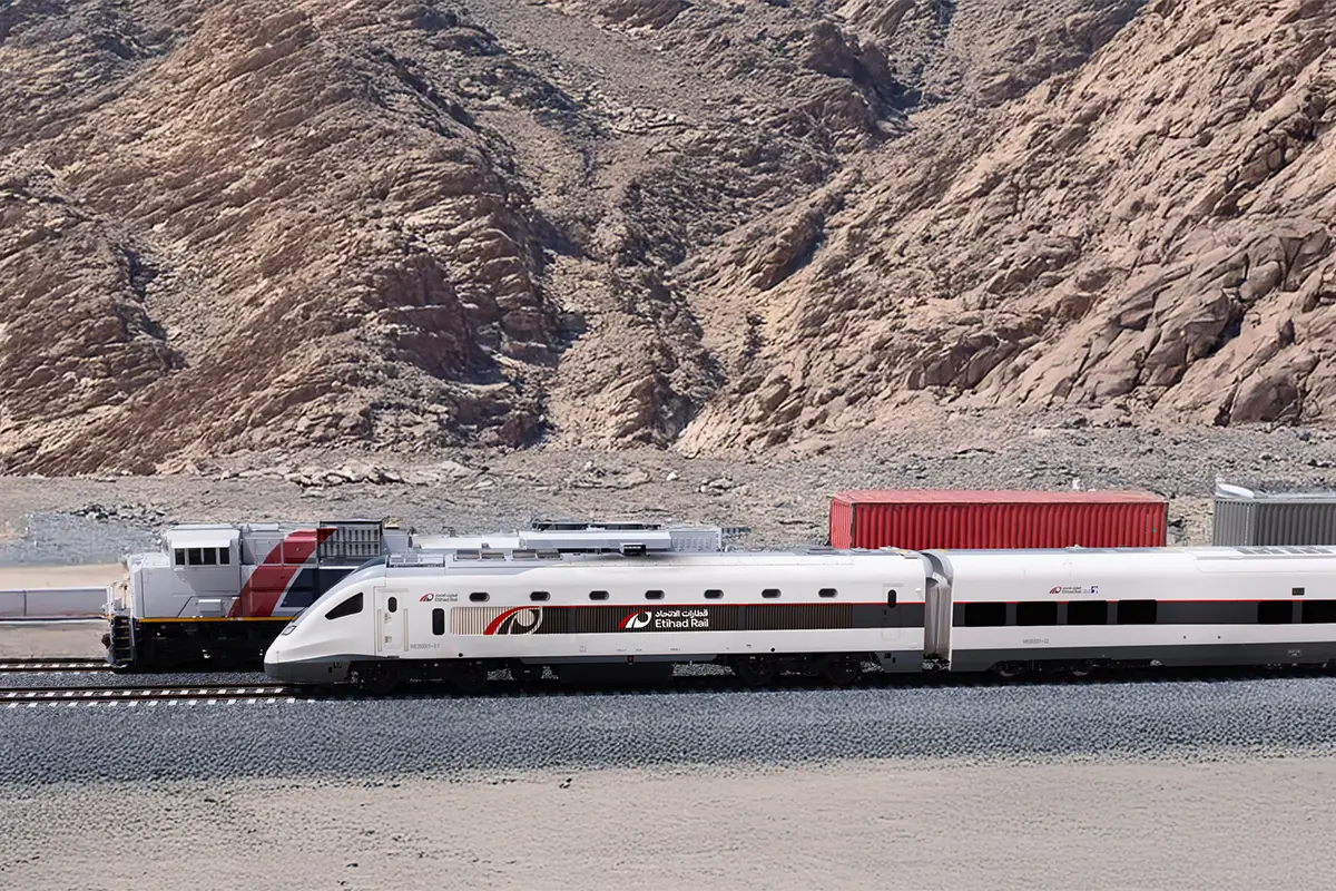 Etihad Rail passenger train travels through a mountainous desert landscape in the United Arab Emirates