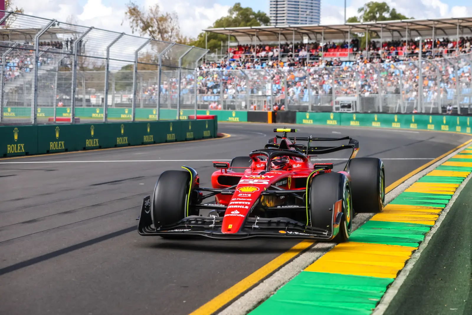 Carlos Sainz driving the Ferrari SF-23 on the Albert Park street circuit during practice at the 2023 Australian Grand Prix in Melbourne, with packed grandstands visible in the background