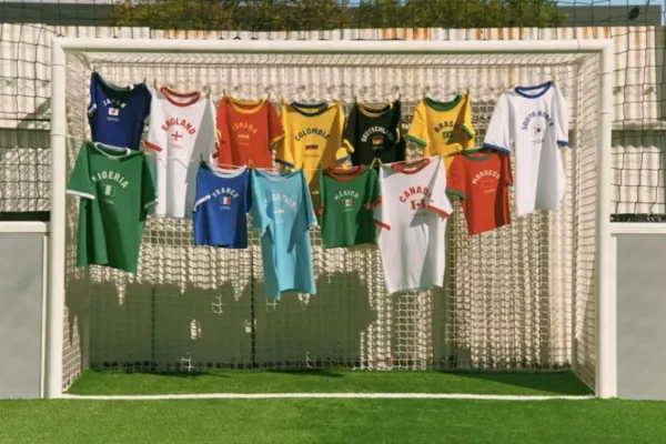 The full Levi's 2026 FIFA World Cup Ringer T-Shirt Collection displayed on a football goal net outdoors, featuring 13 national team colourways including Japan, England, Spain, Colombia, Germany, Brazil, South Korea, Nigeria, France, Argentina, Mexico, Canada, and Morocco