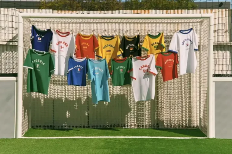 The full Levi's 2026 FIFA World Cup Ringer T-Shirt Collection displayed on a football goal net outdoors, featuring 13 national team colourways including Japan, England, Spain, Colombia, Germany, Brazil, South Korea, Nigeria, France, Argentina, Mexico, Canada, and Morocco