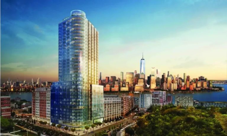 Aerial view of Liberty Harbor residential towers in Jersey City with the Manhattan skyline and One World Trade Center across the Hudson River at sunset.