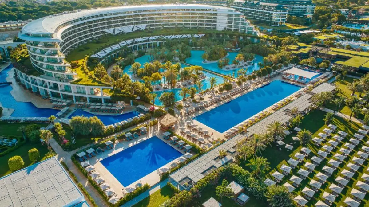 Aerial view of the luxury Maxx Royal Belek Golf Resort with swimming pools, palm trees and beachfront facilities in Antalya, Türkiye.