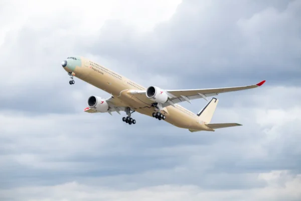 The first Airbus A350-1000ULR built for Qantas climbing through a cloudy sky shortly after takeoff, shown in primer livery without final paint, with landing gear extended and "First A350-1000ULR for Qantas" and "Project Sunrise" titles visible on the forward fuselage.