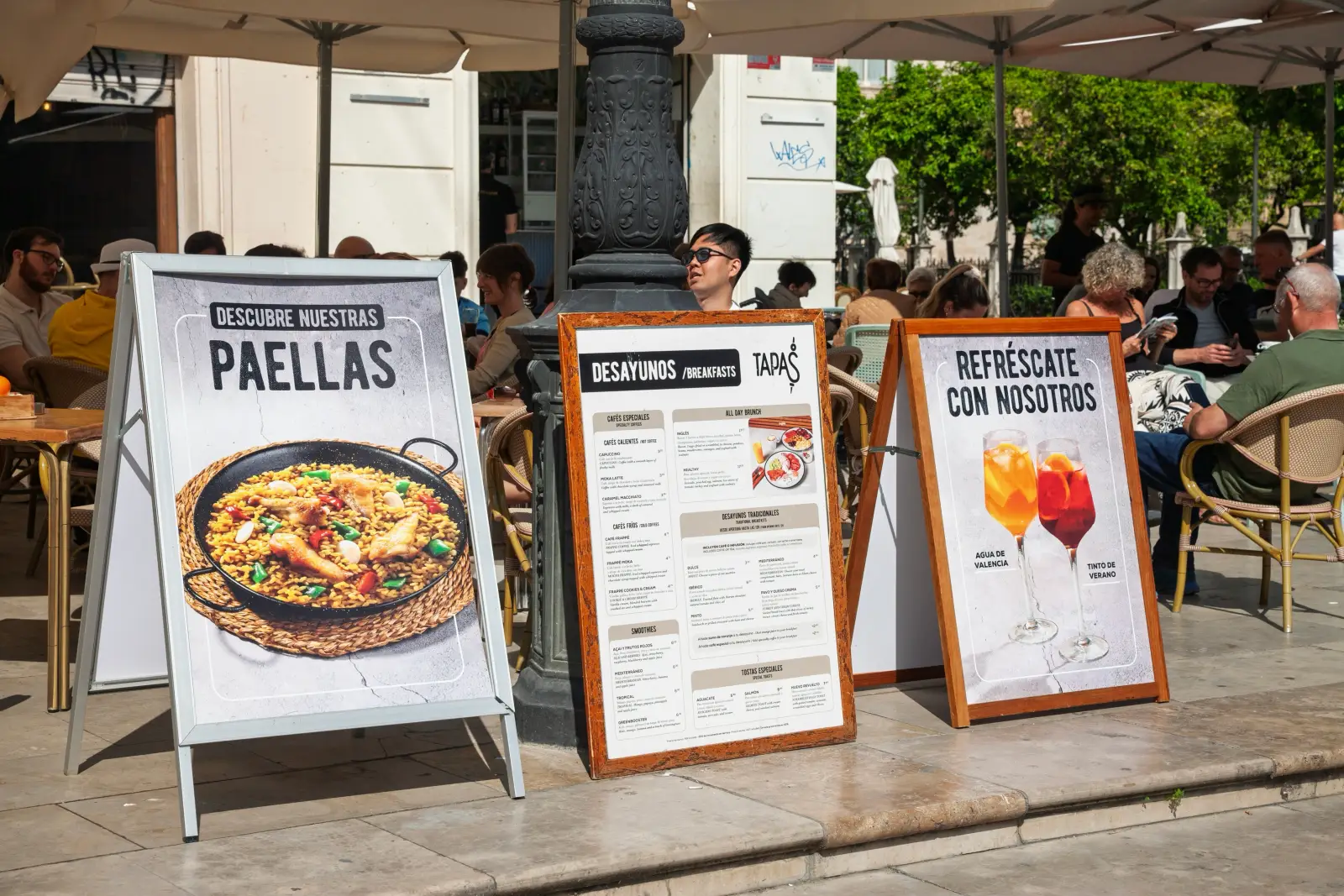 Sidewalk menu boards advertising paellas, tapas breakfast menu and tinto de verano at an outdoor cafe terrace