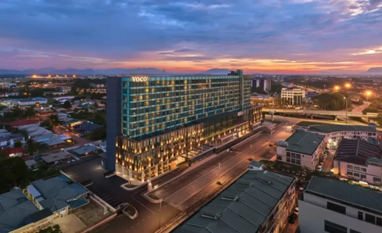 Aerial view of voco Kuching hotel at sunset, showcasing the modern high-rise property and surrounding cityscape in Sarawak, Malaysia.
