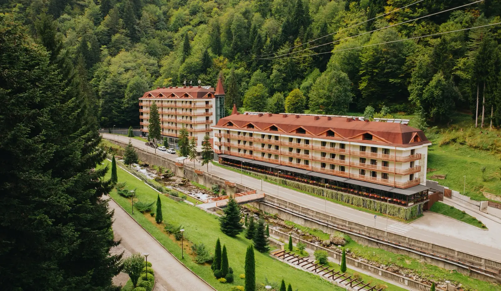 Aerial view of Ensana Sairme South hotel surrounded by forested mountains in the spa town of Sairme, Georgia.