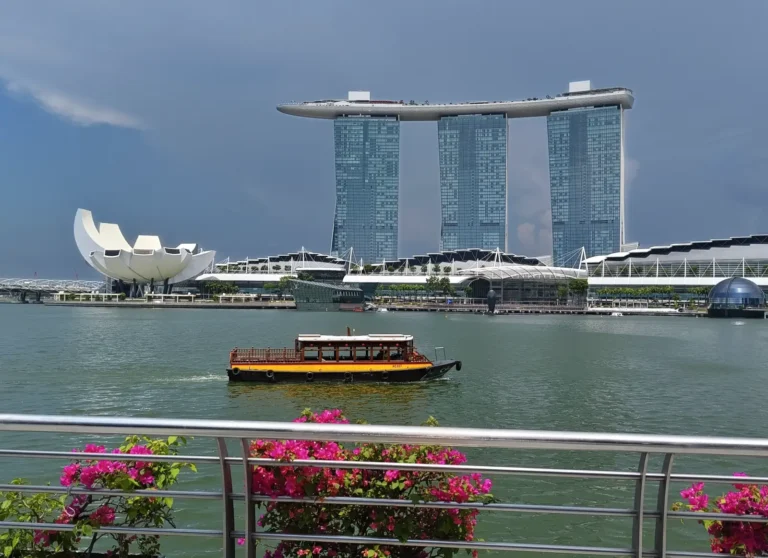 Marina Bay Sands and the ArtScience Museum overlooking Marina Bay in Singapore, with a traditional river boat crossing the waterfront