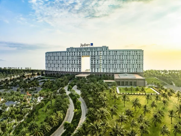 Home 1 Aerial view of Radisson Blu Resort Cam Ranh surrounded by landscaped gardens and palm trees in Vietnam.