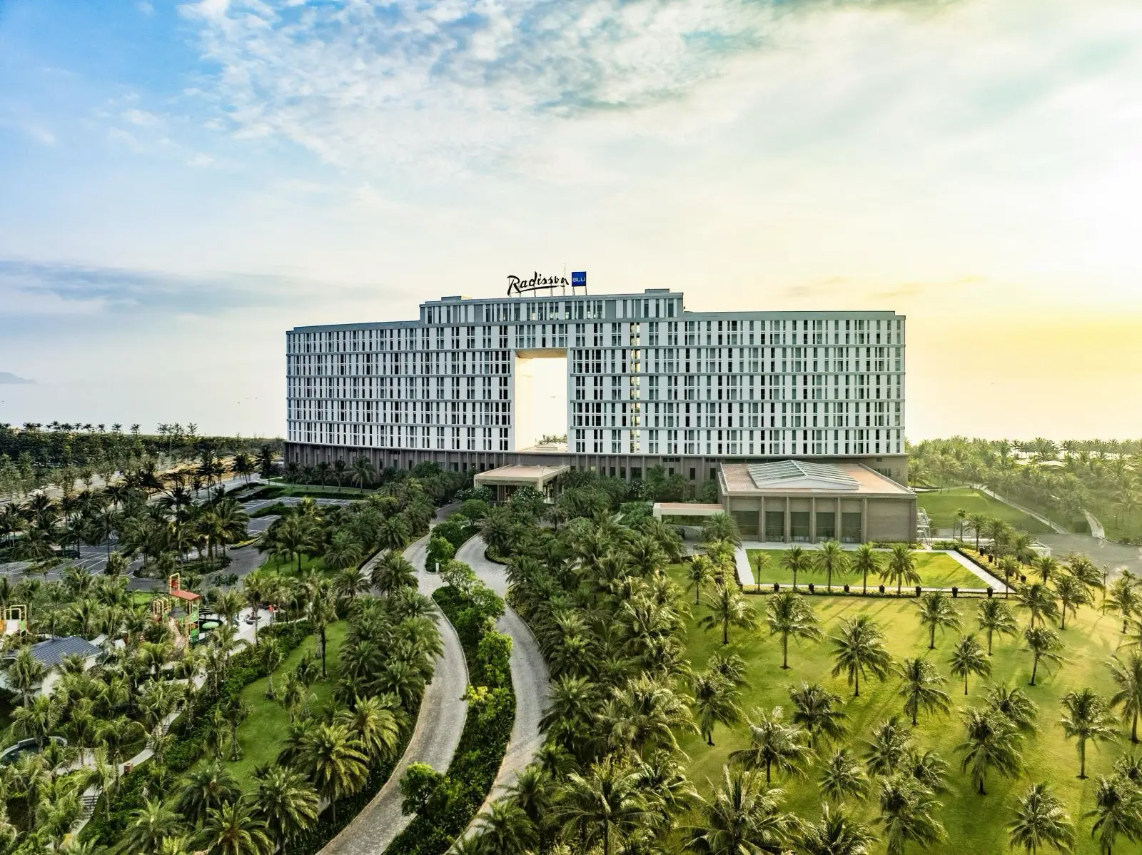 Aerial view of Radisson Blu Resort Cam Ranh surrounded by landscaped gardens and palm trees in Vietnam.