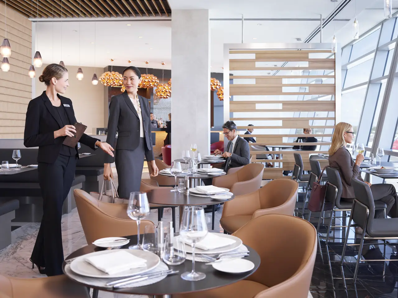 American Unveils Largest-Ever Admirals Club Lounge And Enhanced Flagship Services At Dfw 3 Admirals Club staff seating a customer at a dining table