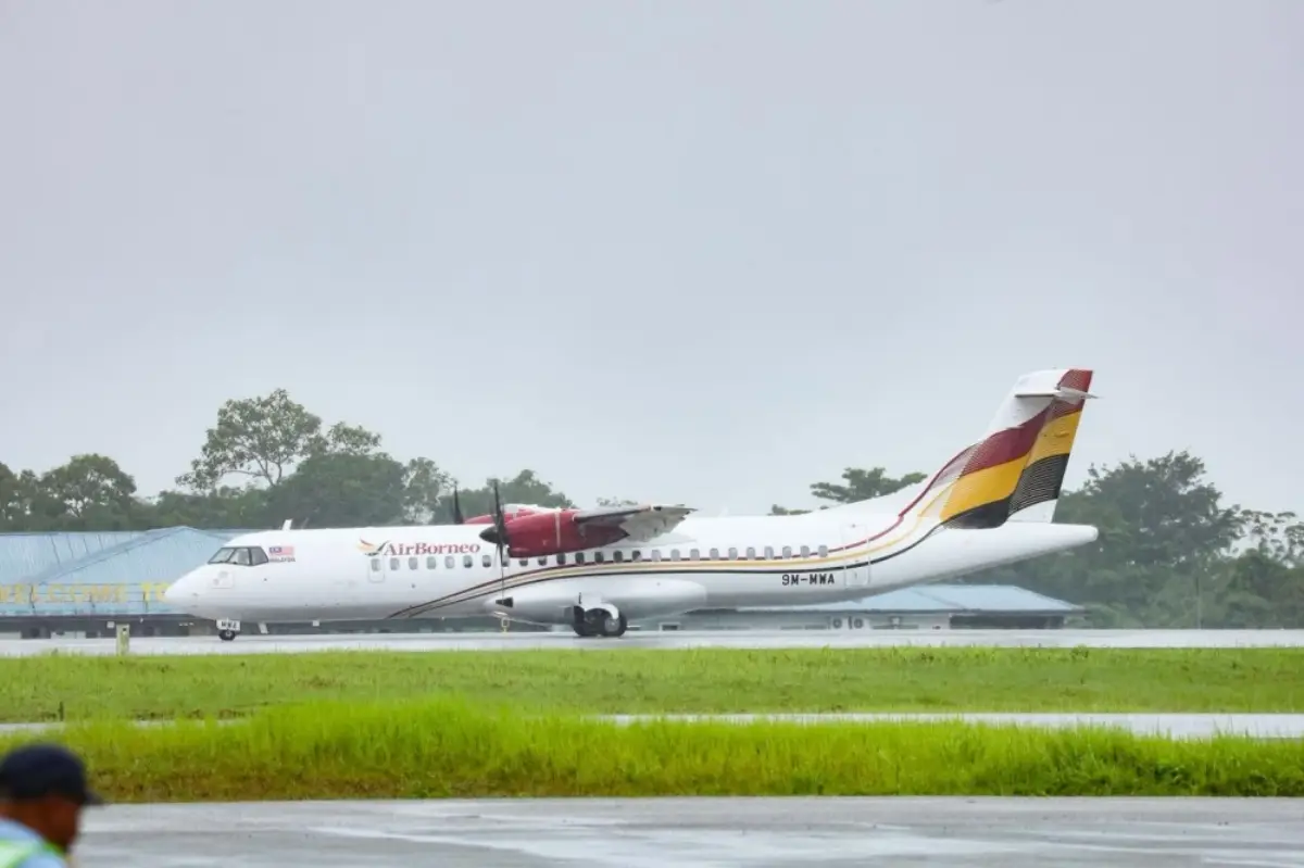 AirBorneo ATR 72 aircraft on the runway at Kuching International Airport during wet weather.
