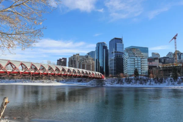 News 28 Winter view of Calgary skyline with the Peace Bridge spanning the Bow River under a clear blue sky.