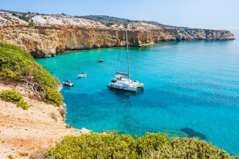 Catamaran anchored in the turquoise waters near Tsigrado Beach on Milos Island in Greece's Cyclades.