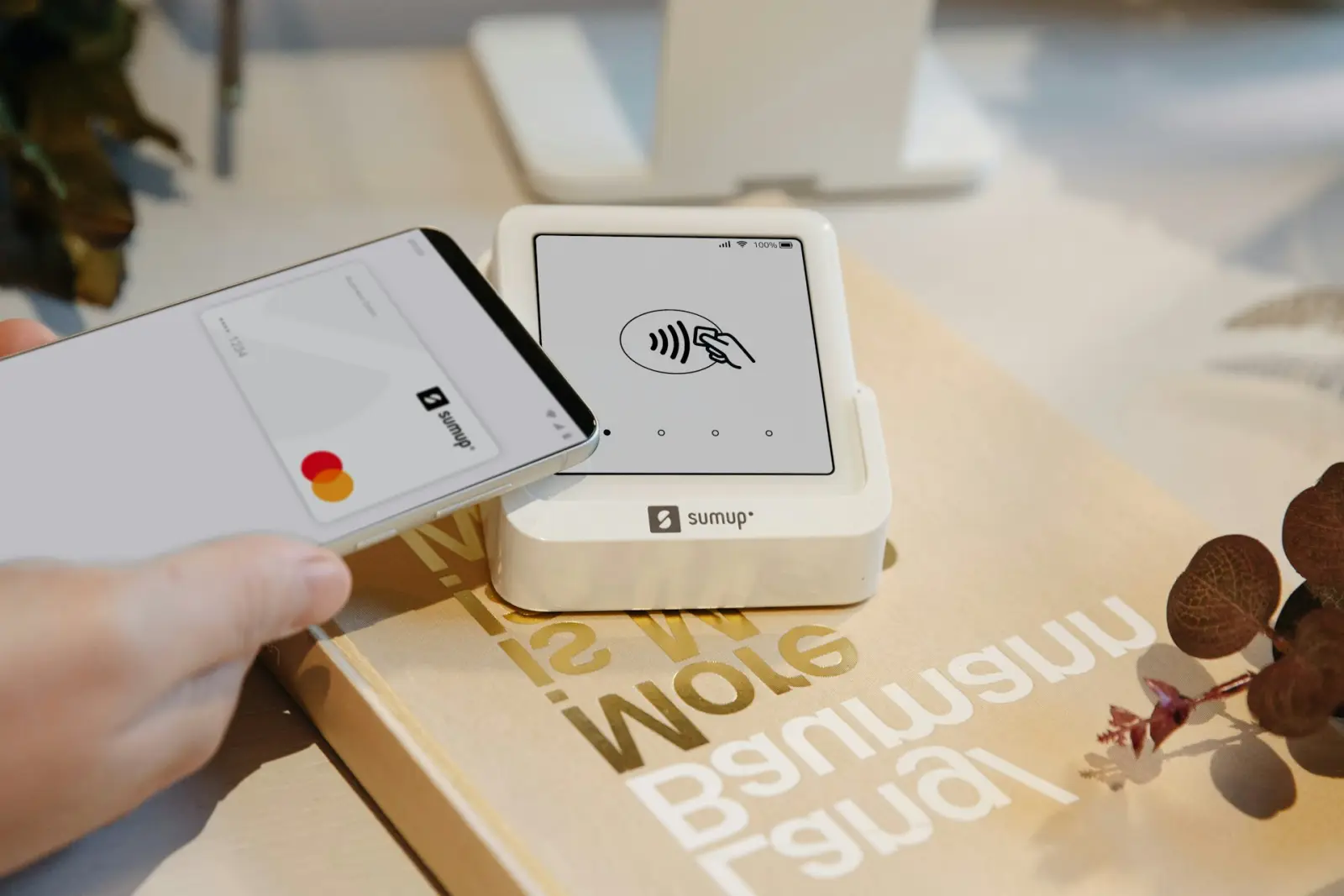 Person making a contactless payment with a smartphone at a SumUp payment terminal.
