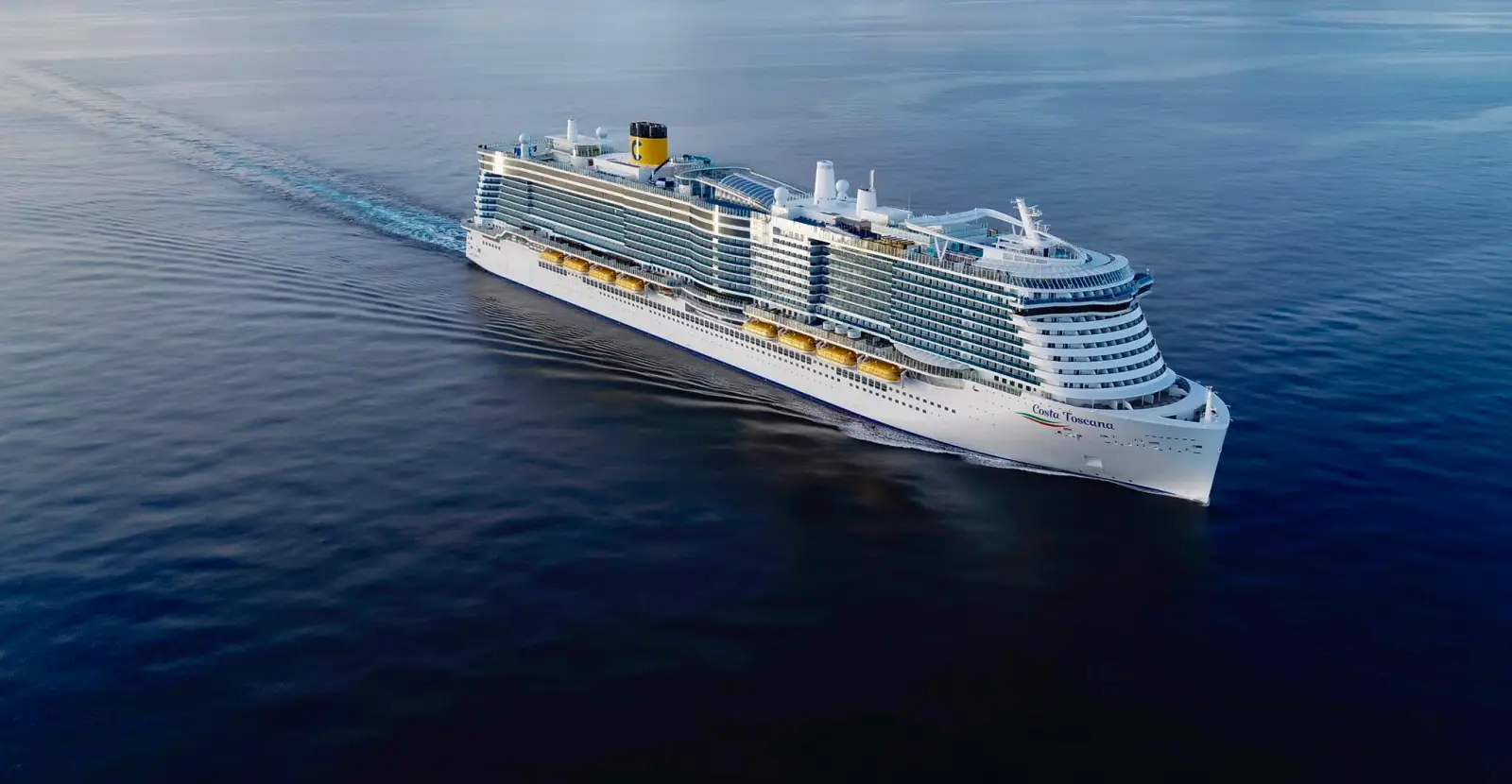 Aerial view of the Costa Toscana cruise ship sailing across calm open sea under clear skies.