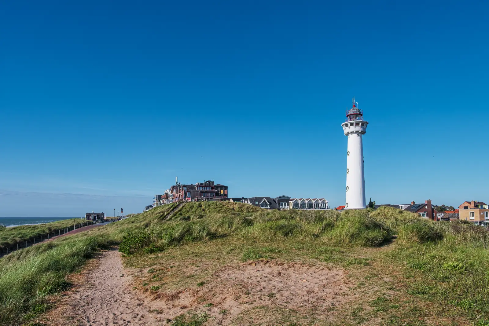 Holidaymakers Warned Of Delays On Routes To Amsterdam And North Sea Beaches 3 The J.C.J. van Speijk Lighthouse stands above the sand dunes in Egmond aan Zee on the Dutch North Sea coast under a clear blue sky.