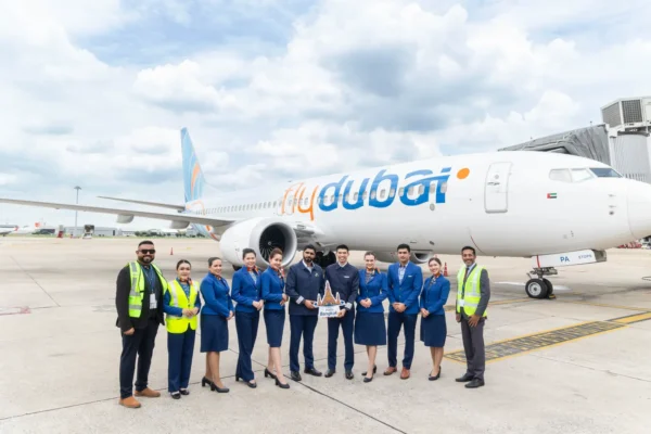 Home 2 flydubai crew and airport staff celebrate the inaugural Dubai to Bangkok flight beside a Boeing 737 MAX at Don Mueang Airport.