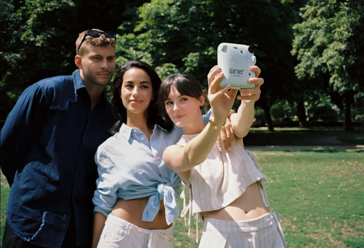 Guests taking a selfie with a Garner branded Instax camera in a park