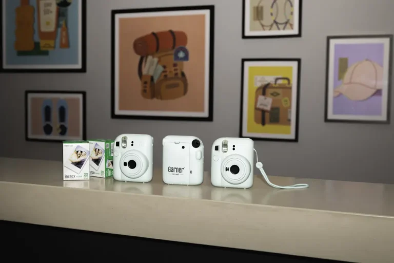 Three white Instax cameras and film displayed at a Garner hotel