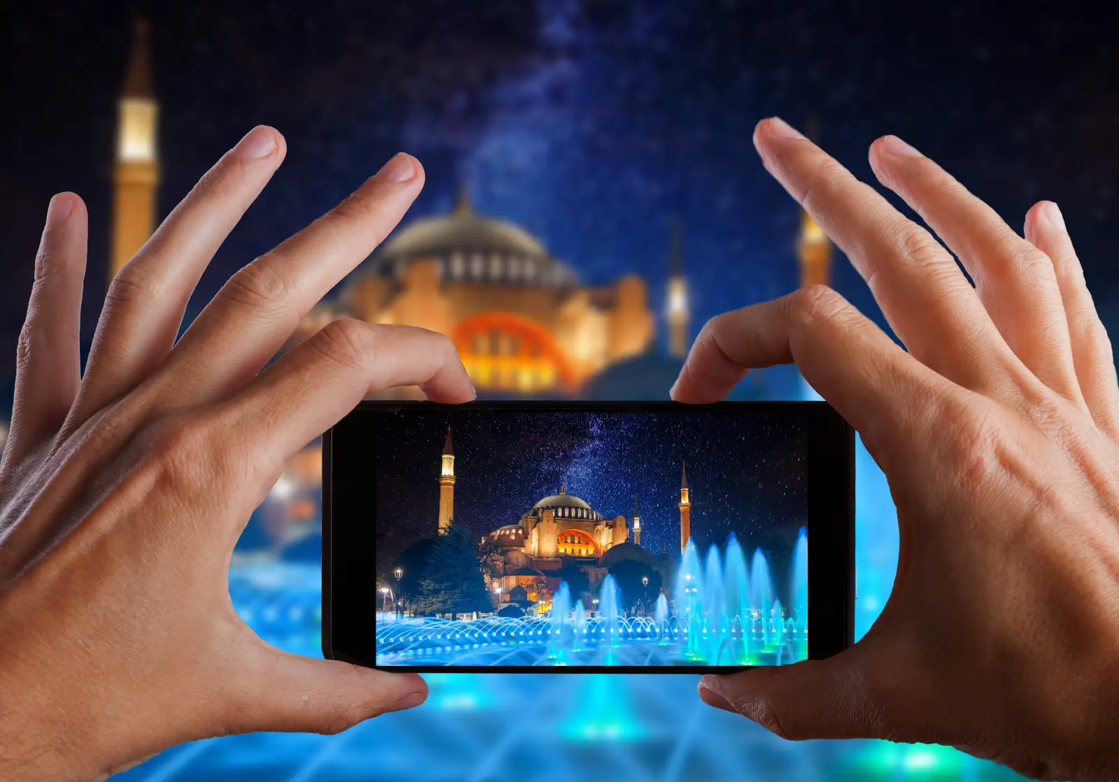 How Social Media Trends Are Influencing Travel Decisions In Istanbul In 2026 4 Hands holding a smartphone to photograph the illuminated Hagia Sophia at night, with colorful fountains in the foreground and a starry sky above.