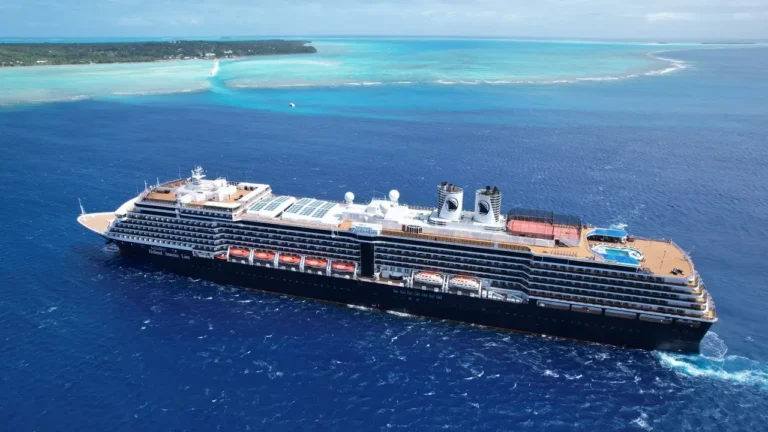 Aerial view of Holland America Line's Zuiderdam sailing through turquoise tropical waters near an island, ahead of the ship's Evolution program refit.