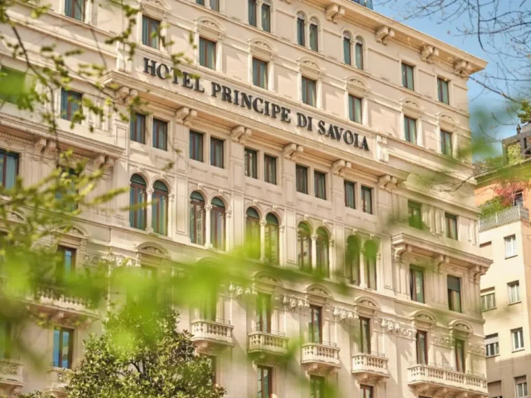 Accommodation 21 Historic façade of Hotel Principe di Savoia in Milan, Italy, viewed through spring greenery